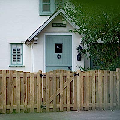 fencing and gate in front of white house with blue door