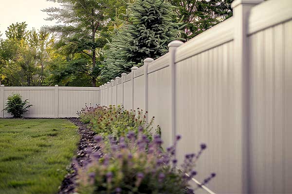 a photo showing a well thought out garden layout design surrounded by a white fence which is also a great garden fence design