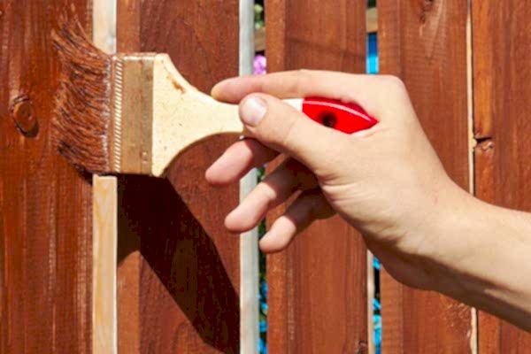 a person's hand paints a fence
