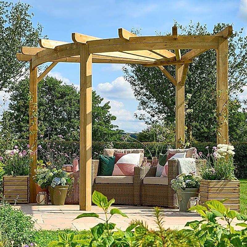 The Forest Premium Radial Wooden Garden Corner Pergola on a patio over garden chairs and planters