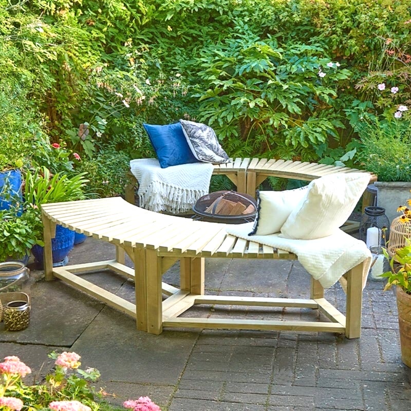 Two Forest Curved Wooden Firepit Benches, placed around a firepit, with blue and cream cushions