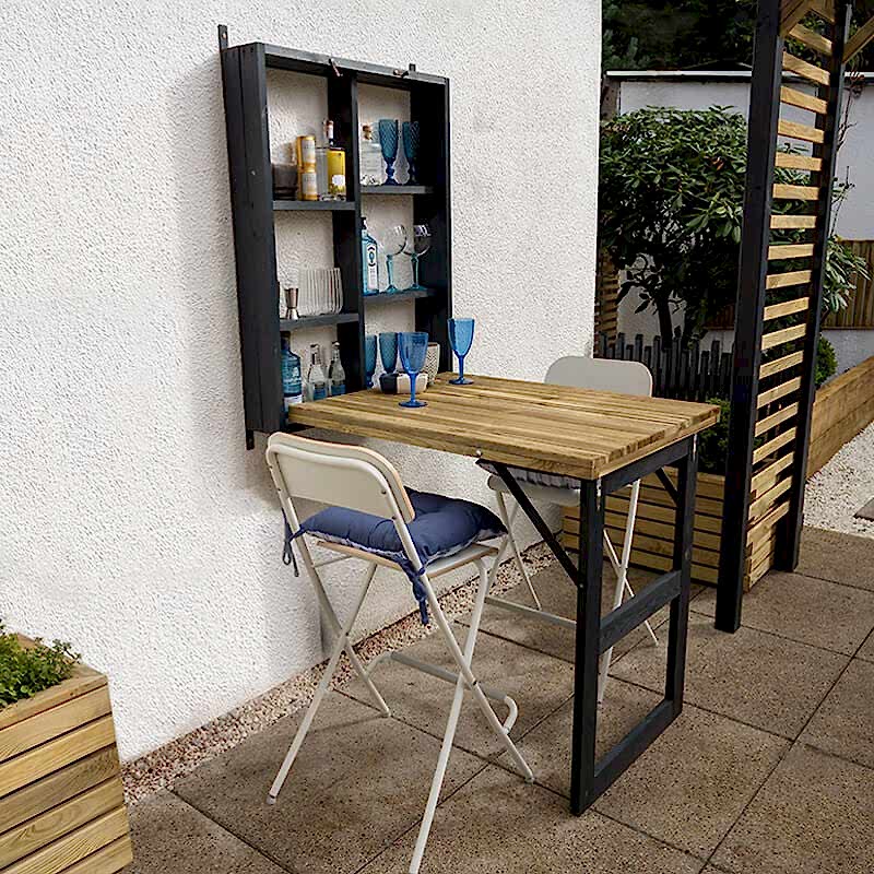 The Forest Wooden Fold Down Garden Walla Bar, on a patio with two bar chairs
