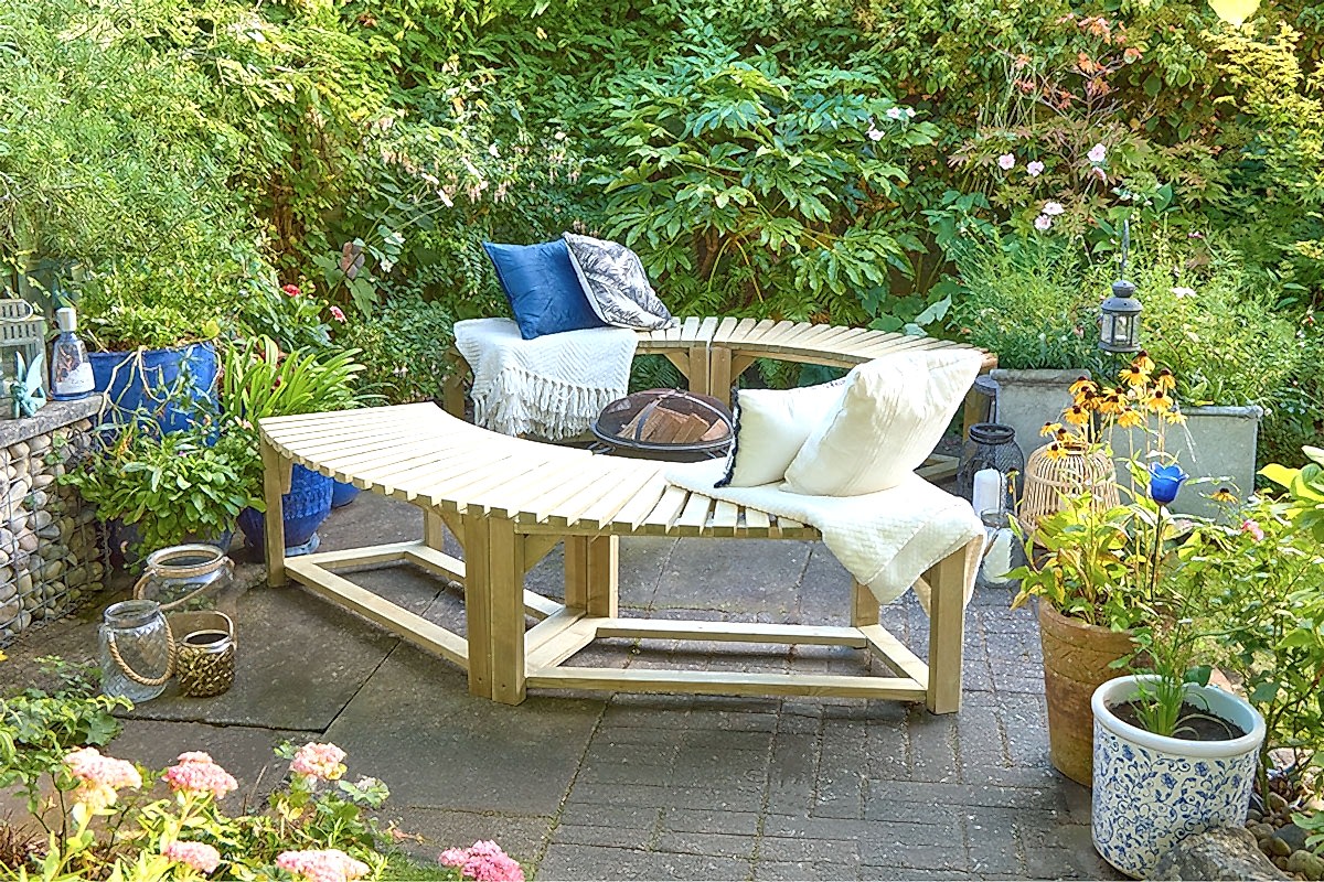 Four Forest Curved Wooden Benches around a firepit in a garden with blue and white cushions