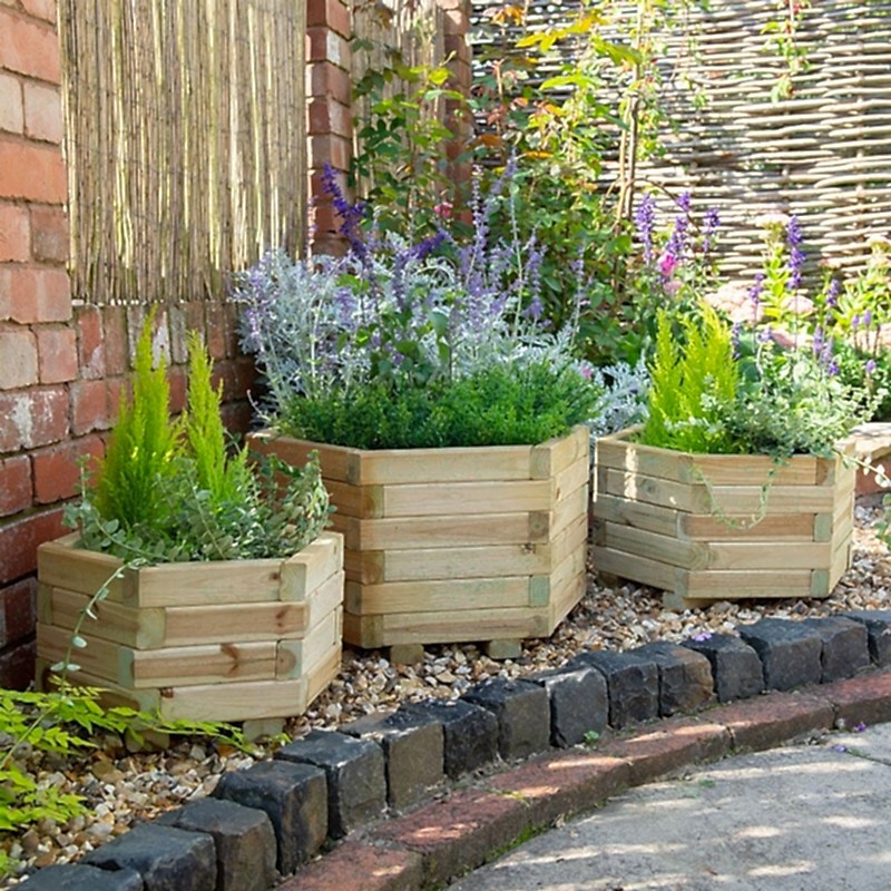 A set of three Forest York Hexagonal Wooden Garden Planters with plants and flowers