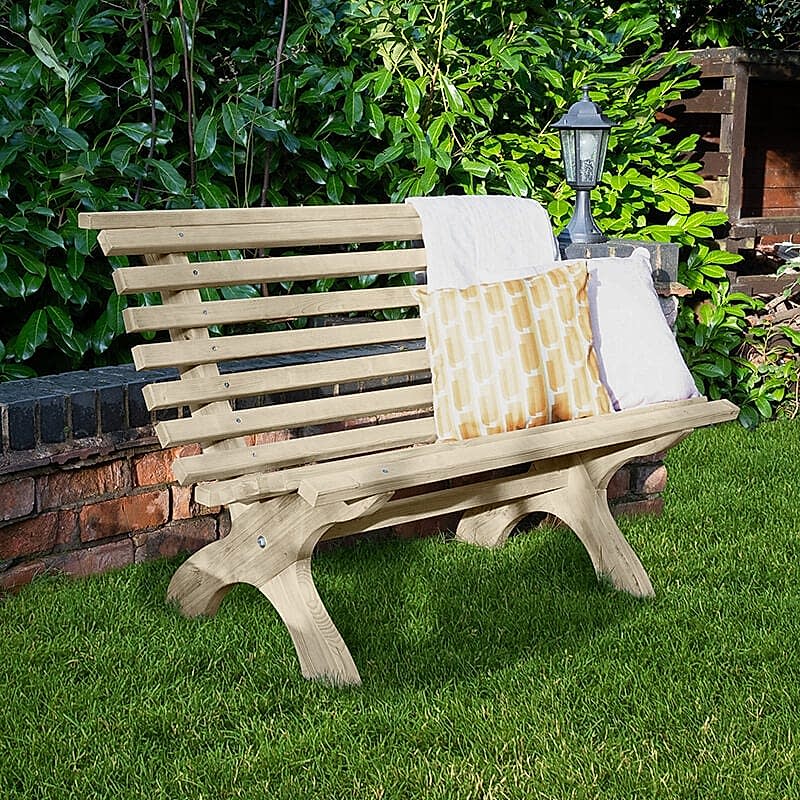 A Forest Kuba Curved Wooden Garden Bench with cushions, in a garden