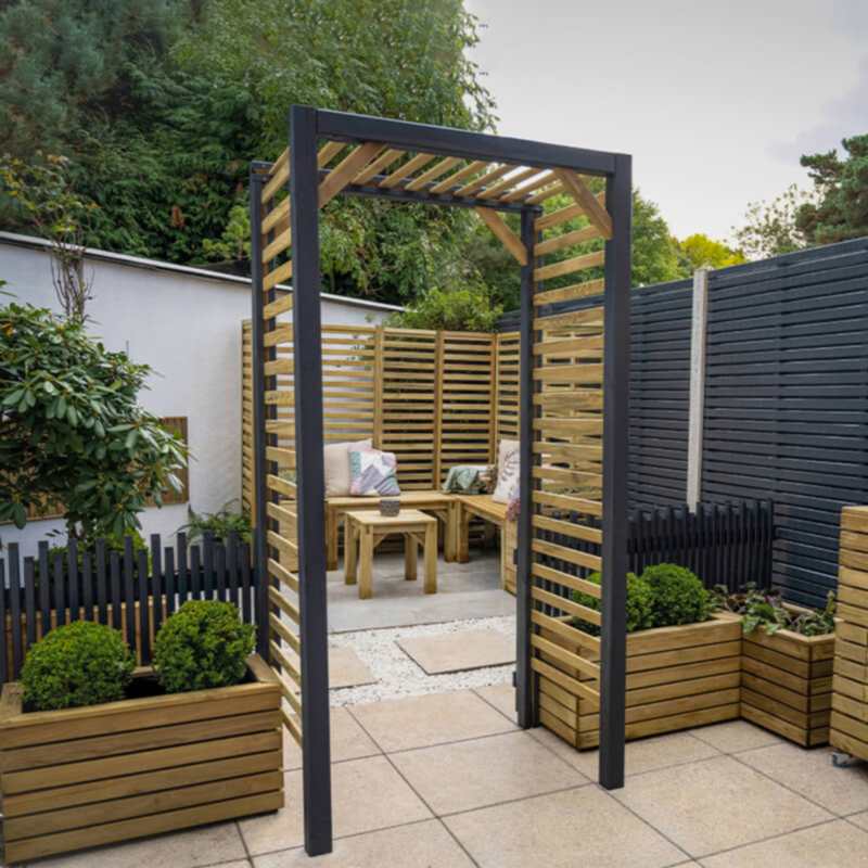 The Forest Contemporary Slatted Garden Arch on paving with planters and a wooden fence