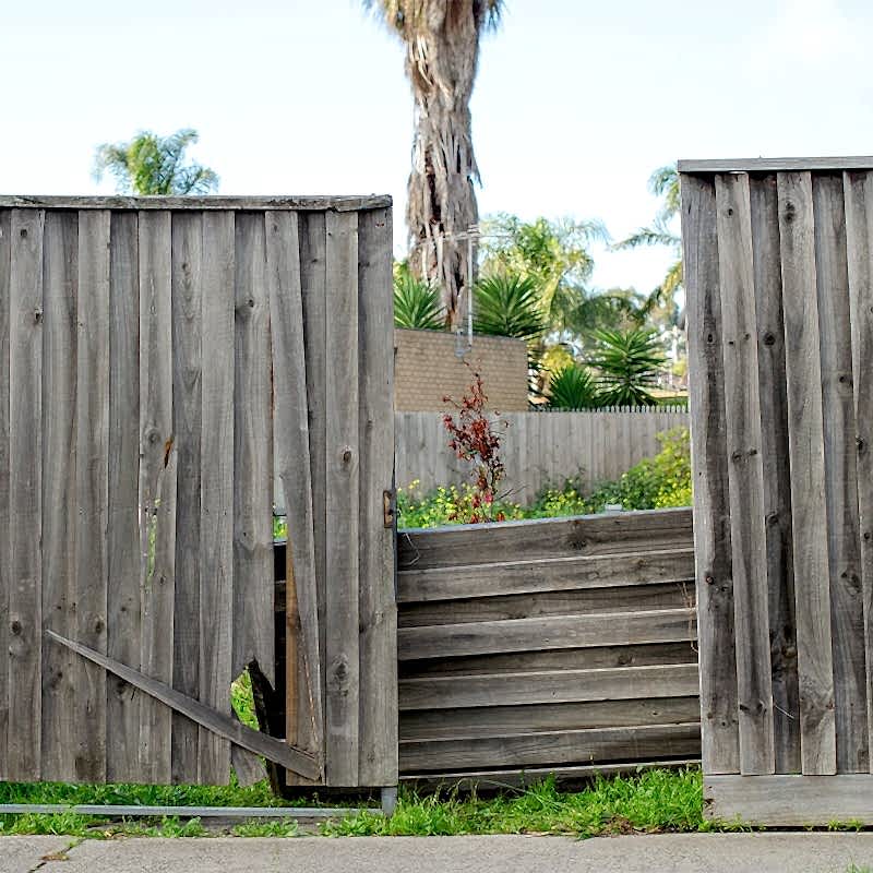 an old run of fencing that is far past the point of fixing a fence and is in desparate need of fence panel replacement
