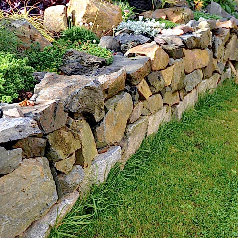 a photo of a stone wall being used as eco-friendly fence panels that are made using sustainable fence materials to create eco-friendly fencing