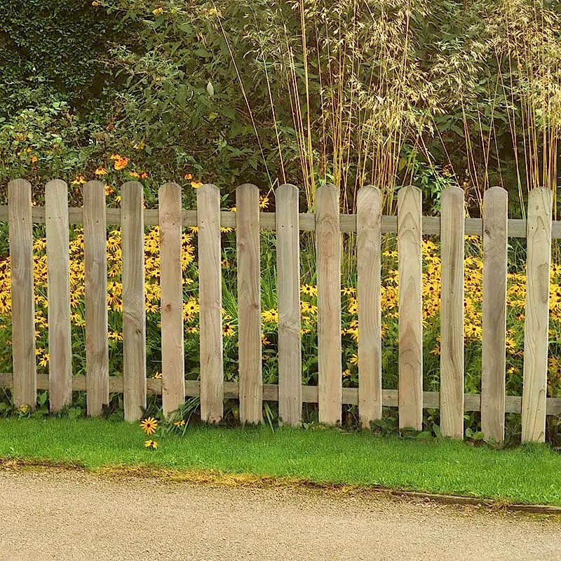 a photo showing a fencing run with some wonderful fence landscaping from our list of simple fence line landscaping ideas including the best plants for fence lines