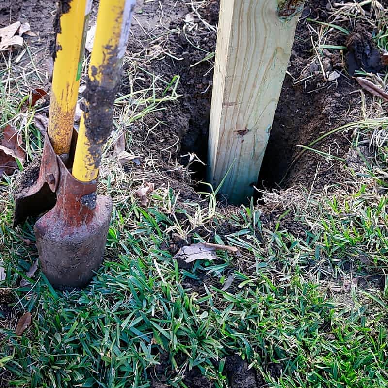 photo of someone digging a hole for a fence post