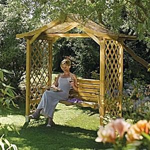 A woman in a white dress sat on the Rowlinson Dartmouth Wooden Swing Seat.