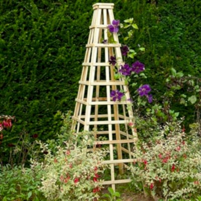 Buy the Forest Pressure Treated Garden Obelisk Trellis 1.8m now A wooden garden obelisk with purple flowers climbing up trellis sides